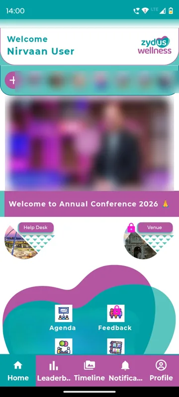 Home with a Welcome header, a reels strip with an add button, a welcome video panel blurred, a conference banner and Help Desk and Venue badges